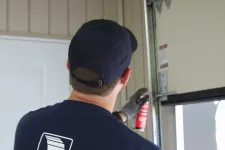 A man showing how to lubricate garage door rollers